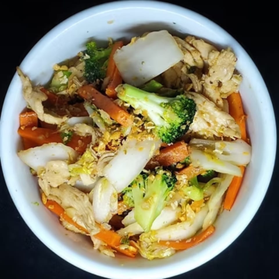 A white bowl filled with Maya Thai Eatery's stir-fried chicken, broccoli, carrots, and cabbage.